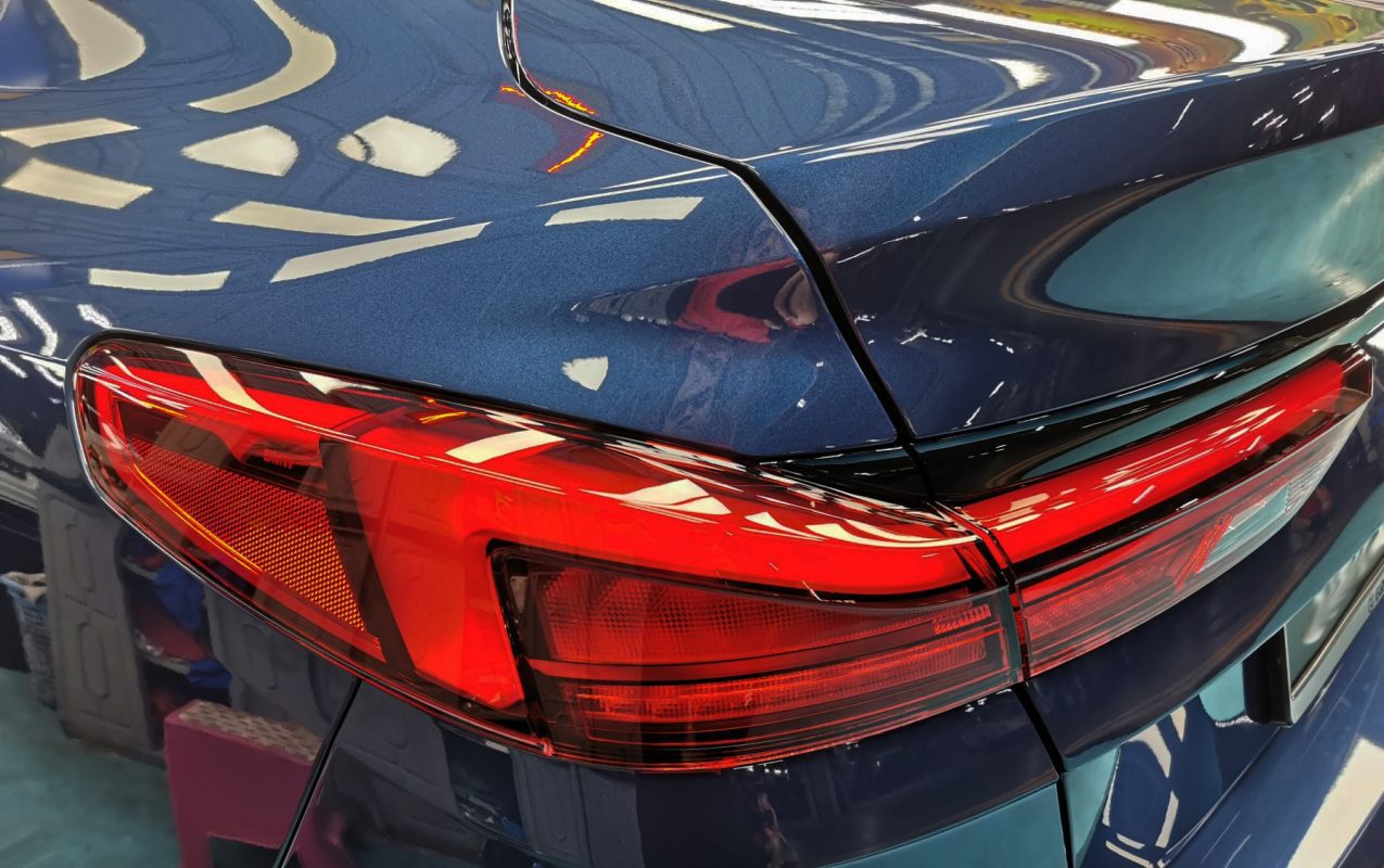 The coated bonnet of the BMW 2 Series under workshop lighting.