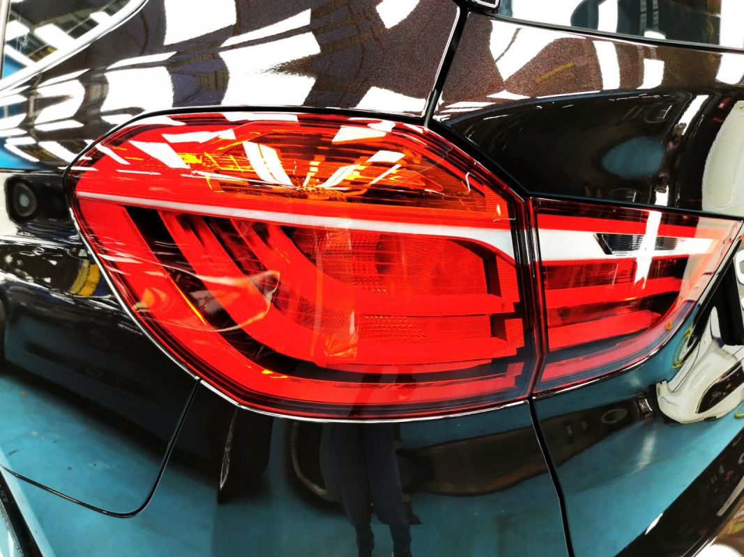 The coated bonnet of the BMW 216 GT under workshop lighting.