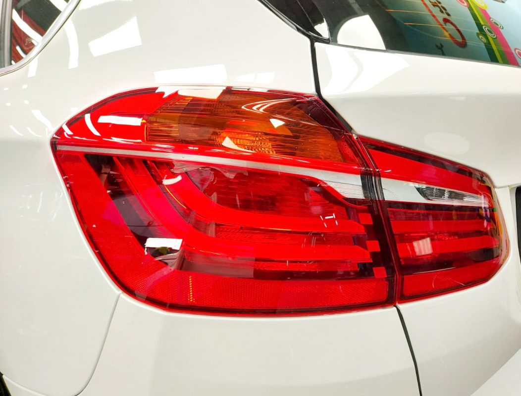 The coated bonnet of the BMW 216i under workshop lighting.