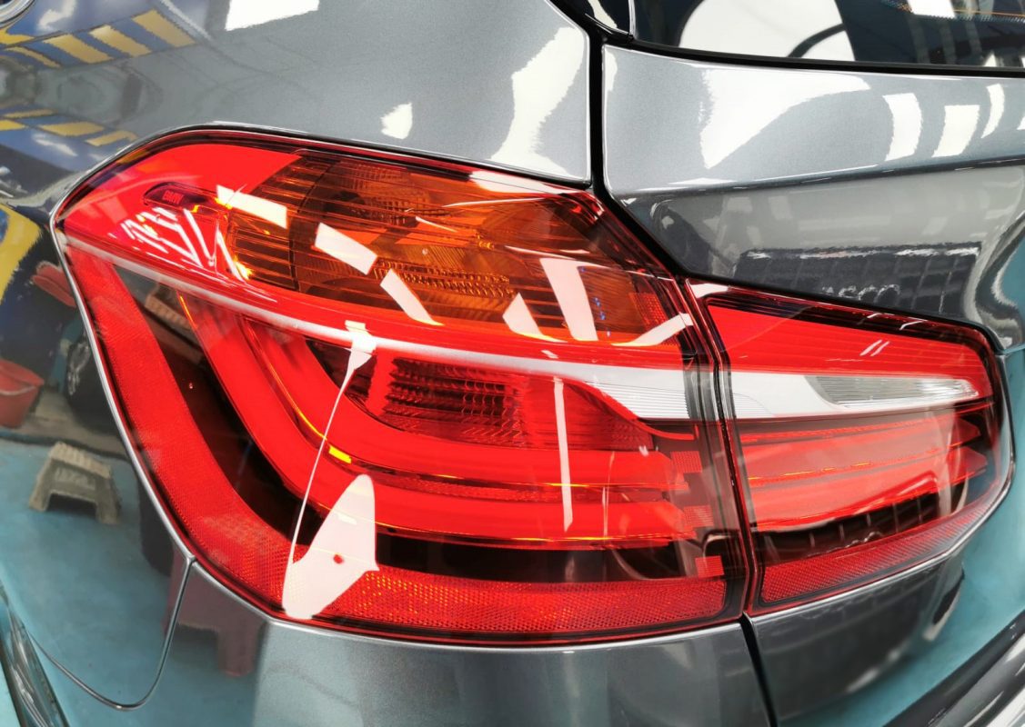 The coated bonnet of the BMW 216i under workshop lighting.