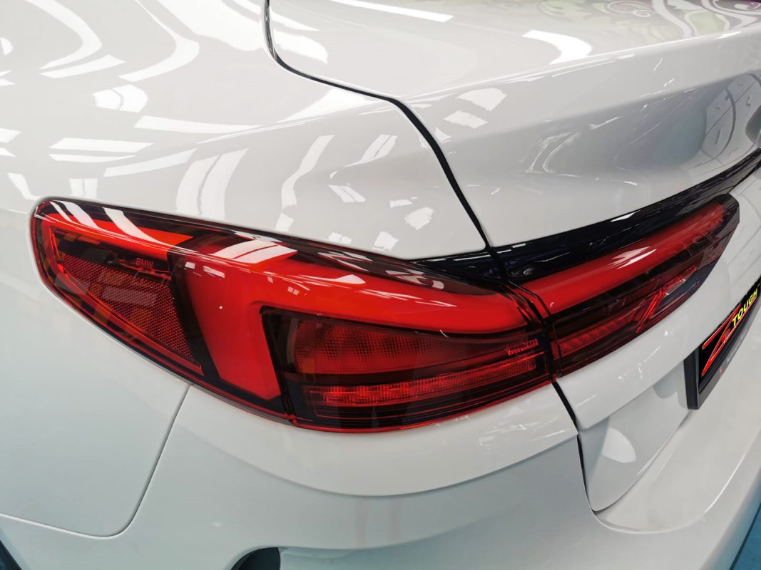 The coated bonnet of the BMW 216i under workshop lighting.
