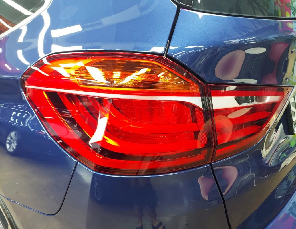 The coated bonnet of the BMW 216i GT under workshop lighting.