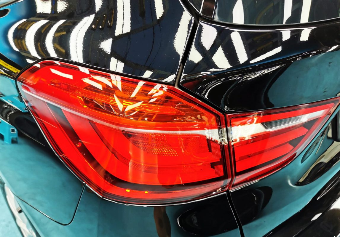 The coated bonnet of the BMW 216i GT under workshop lighting.