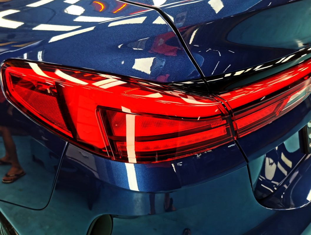 The coated bonnet of the BMW 216i under workshop lighting.