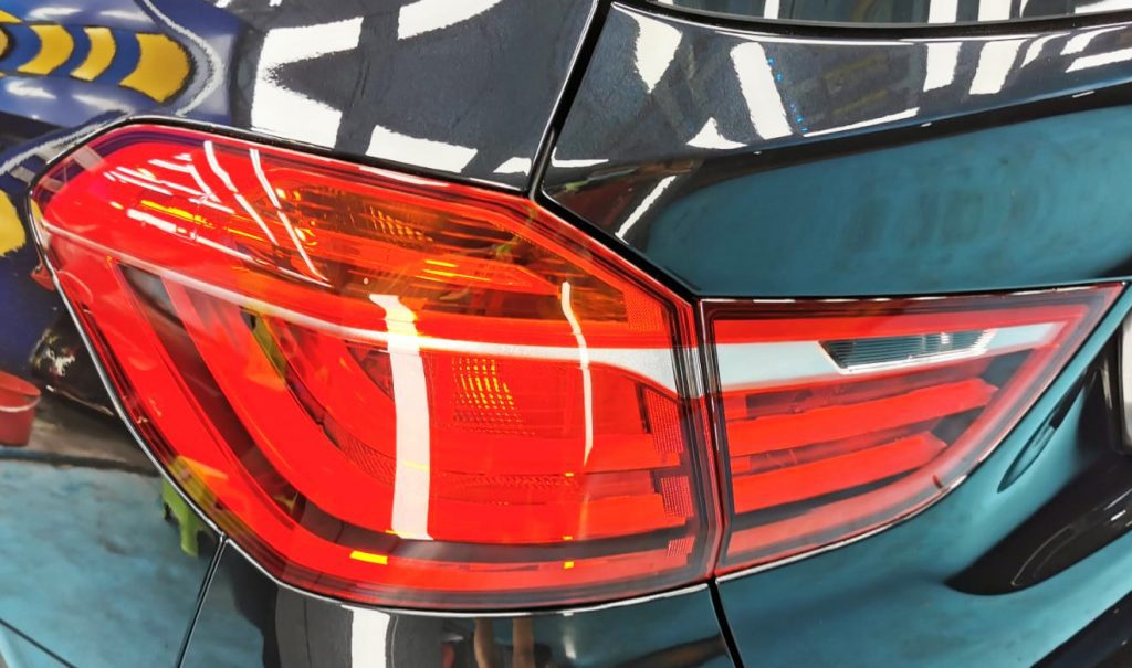 The coated bonnet of the BMW 216i under workshop lighting.