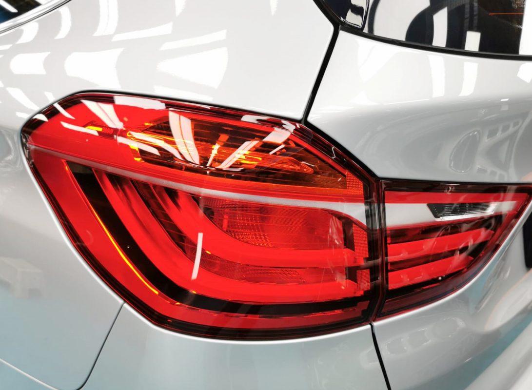 The coated bonnet of the BMW 216i under workshop lighting.