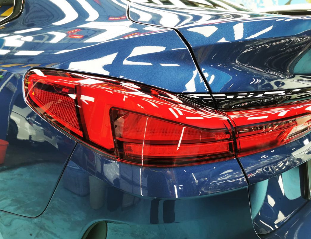 The coated bonnet of the BMW 216i under workshop lighting.