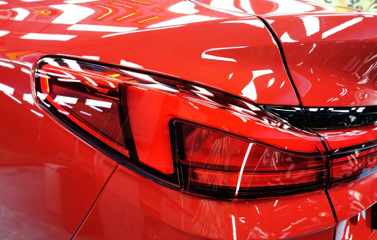 The coated bonnet of the BMW 216i under workshop lighting.