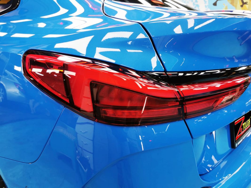 The coated bonnet of the BMW 218i under workshop lighting.