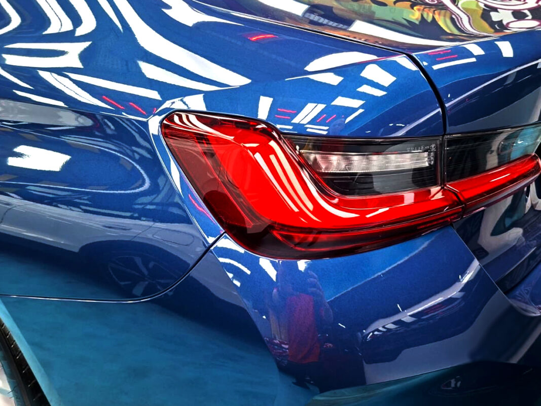 The coated bonnet of the BMW 3 Series under workshop lighting.