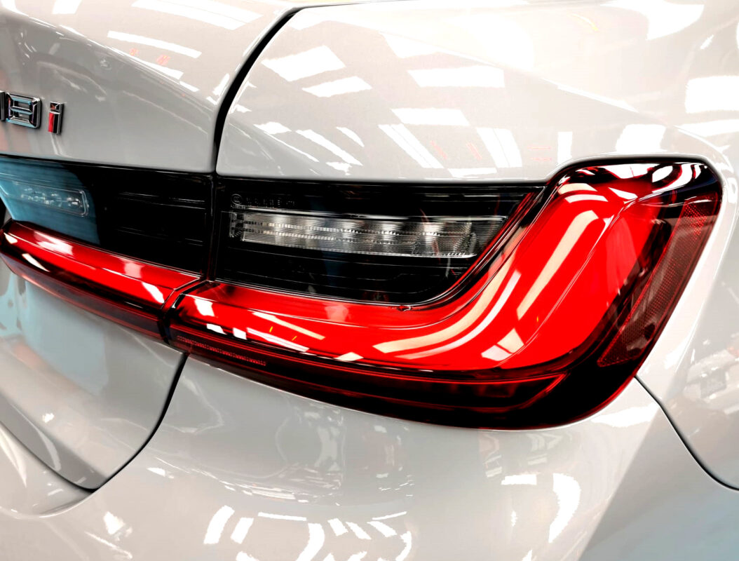 The coated bonnet of the BMW 3 Series under workshop lighting.