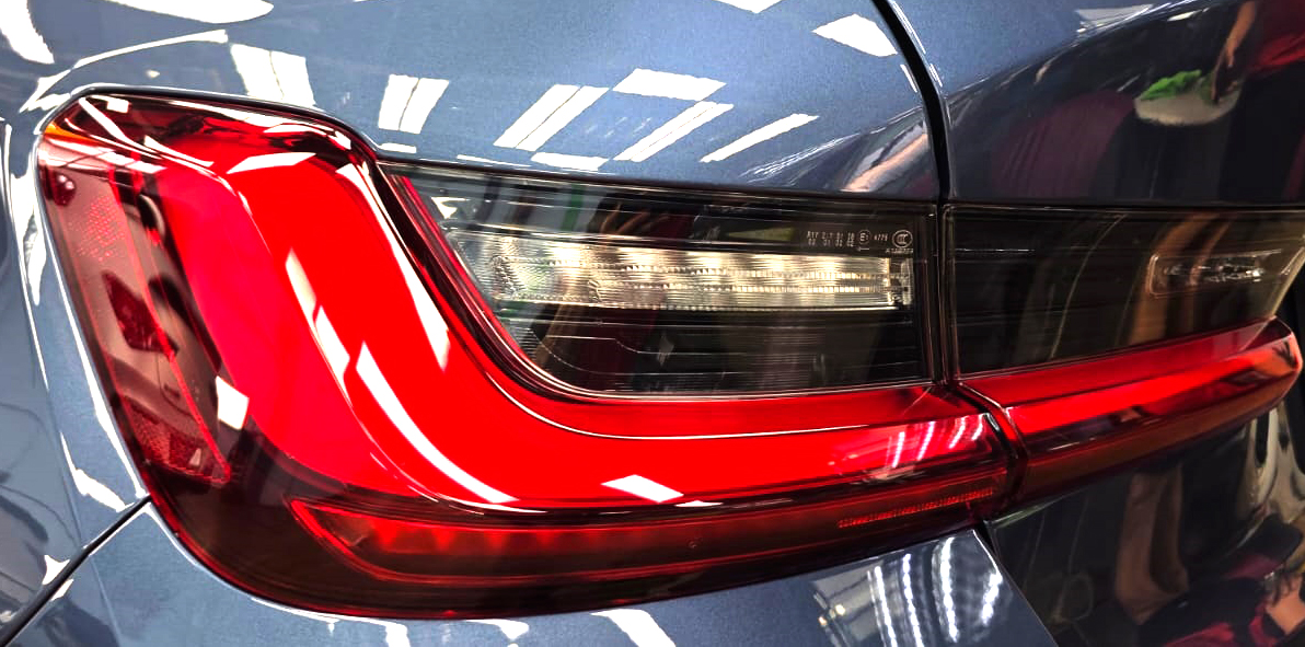 The coated bonnet of the BMW 3 Series under workshop lighting.