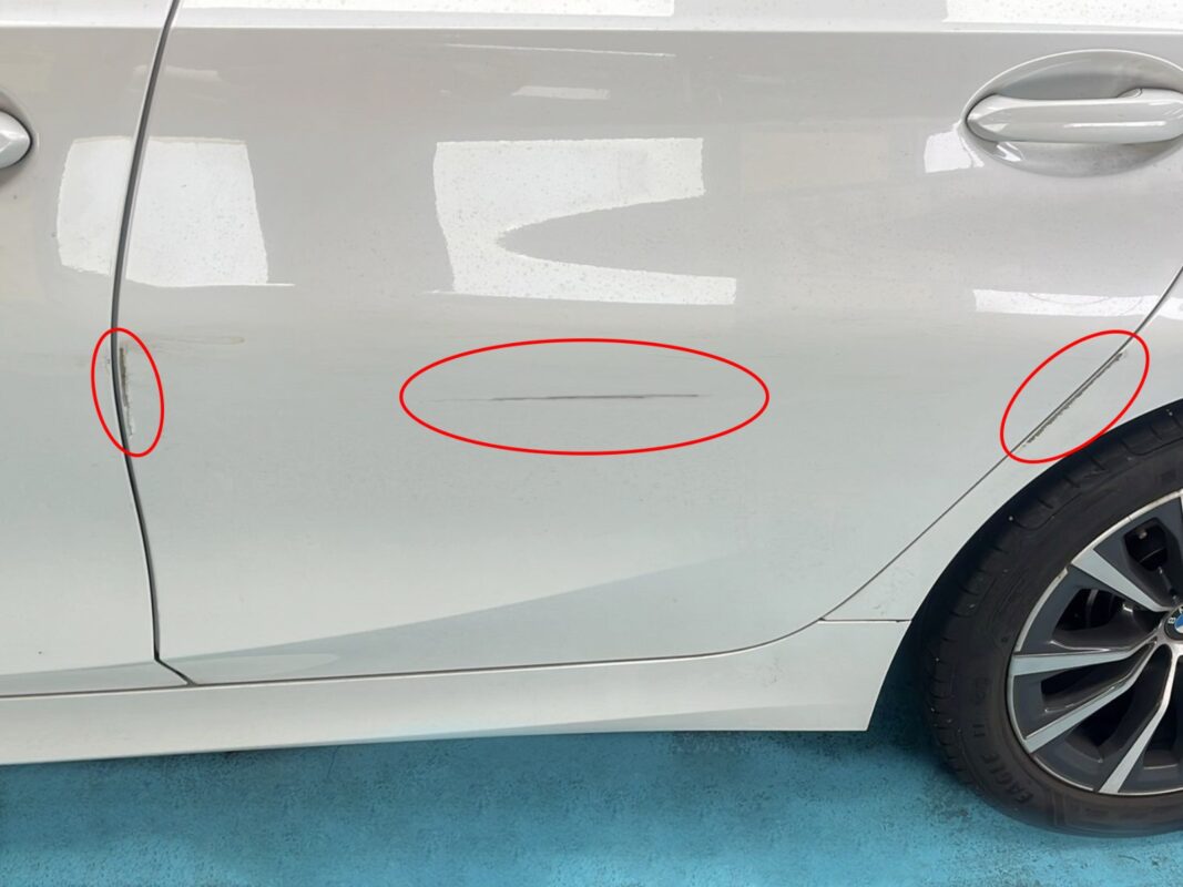 Deep scratches circled on the BMW 3 Series door, recorded before repair.