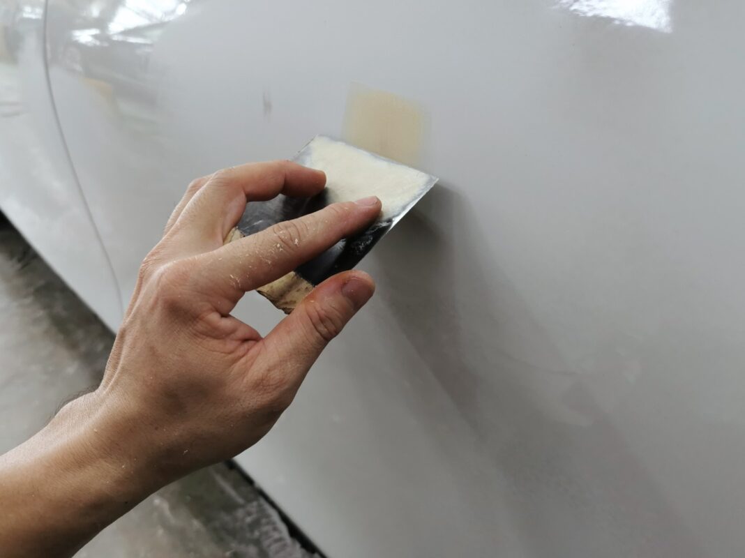 Body filler levelling a scratched panel on the BMW 3 Series before paint.