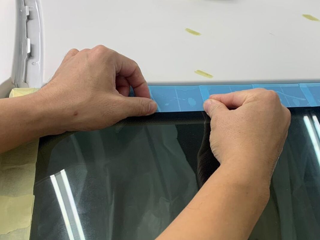 Masking the BMW 3 Series glass and trim before the spray booth.