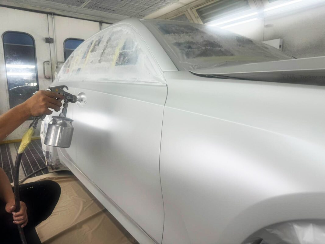 A Revol Carz painter laying the new coat onto the BMW 3 Series in the spray booth.