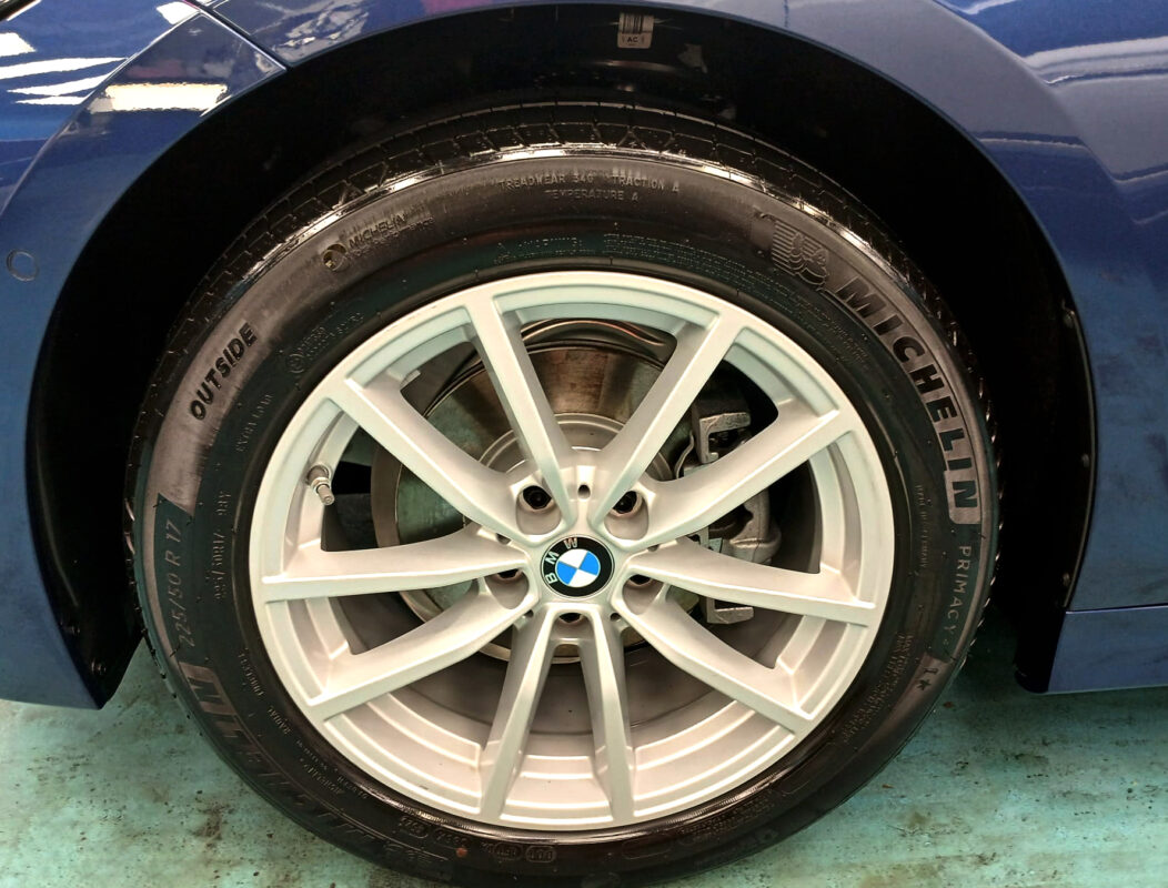 The coated bonnet of the BMW 3 Series under workshop lighting.