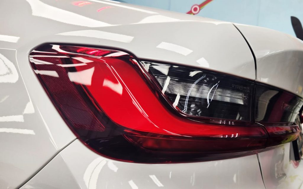 The coated bonnet of the BMW 3 Series under workshop lighting.