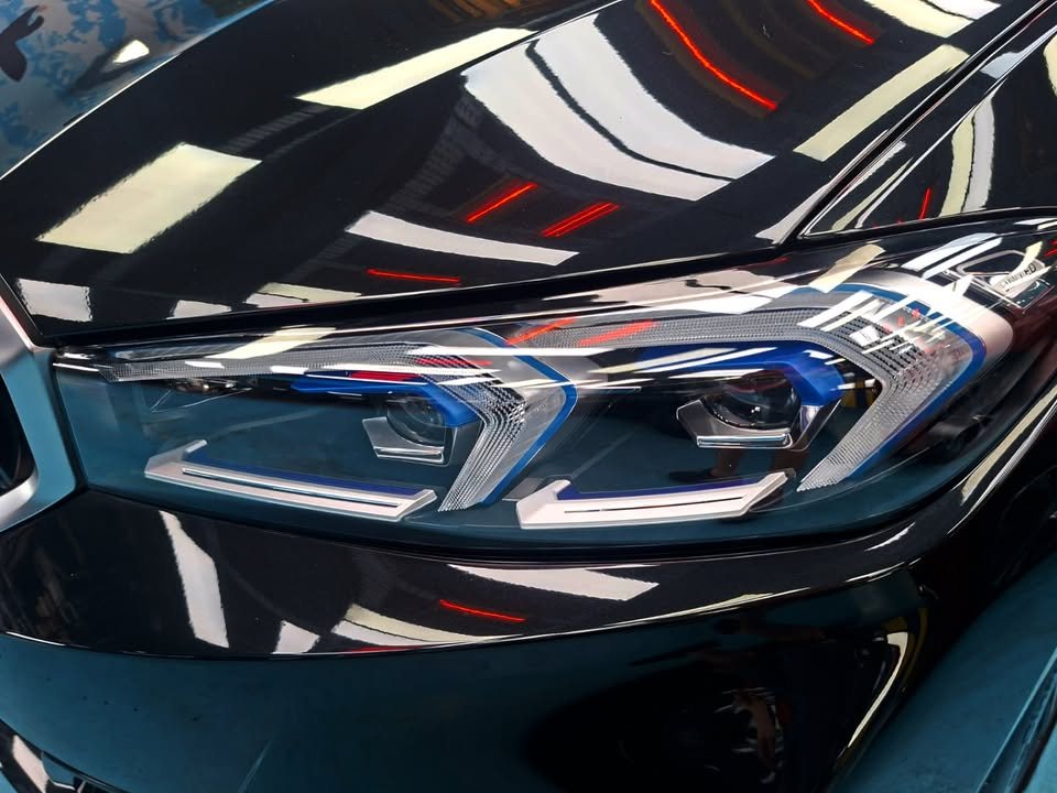 Close-up of the LED headlight and black bonnet edge with sharp reflections.