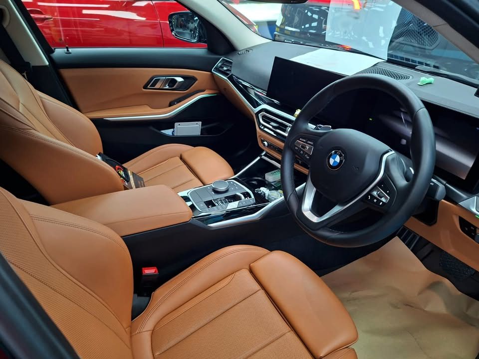 Interior with tan leather seats, steering wheel and curved dashboard screen.