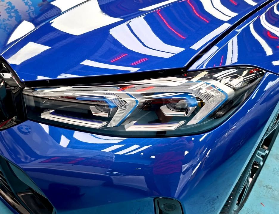Close-up of the headlamp with light reflections on the blue bonnet.