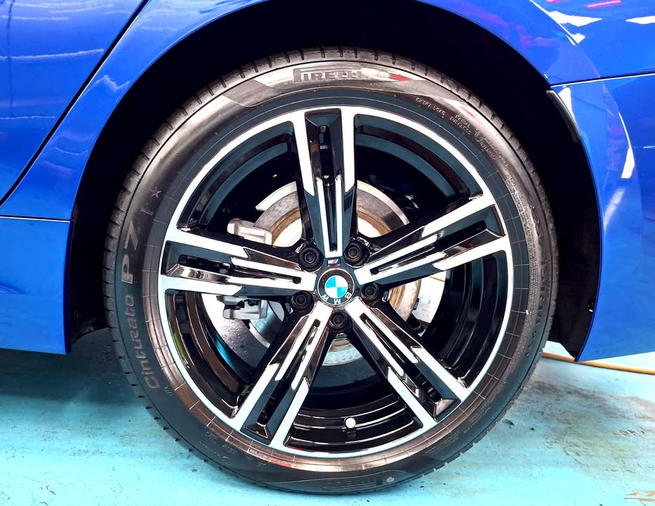 Two-tone five-spoke alloy wheel under the blue wheel arch.