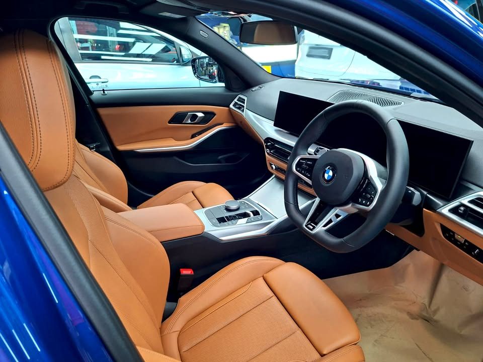 Interior view of the tan leather seats, steering wheel and curved display.
