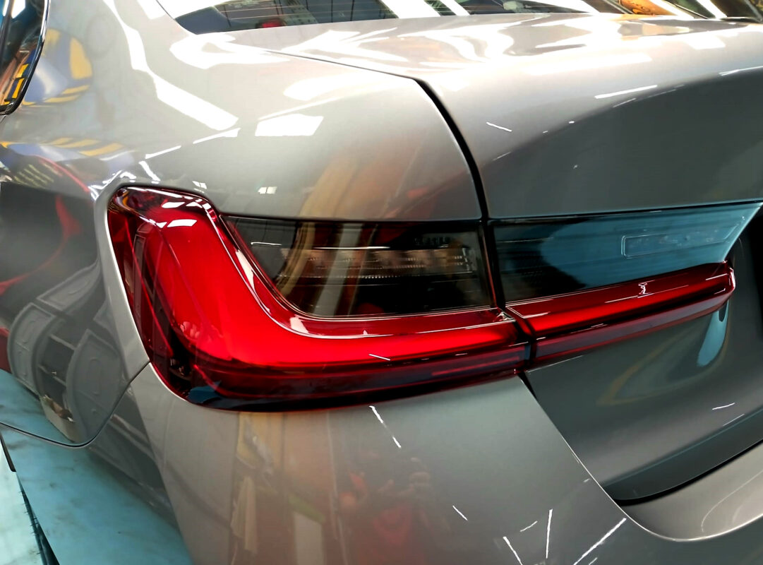 The coated bonnet of the BMW 3 Series under workshop lighting.
