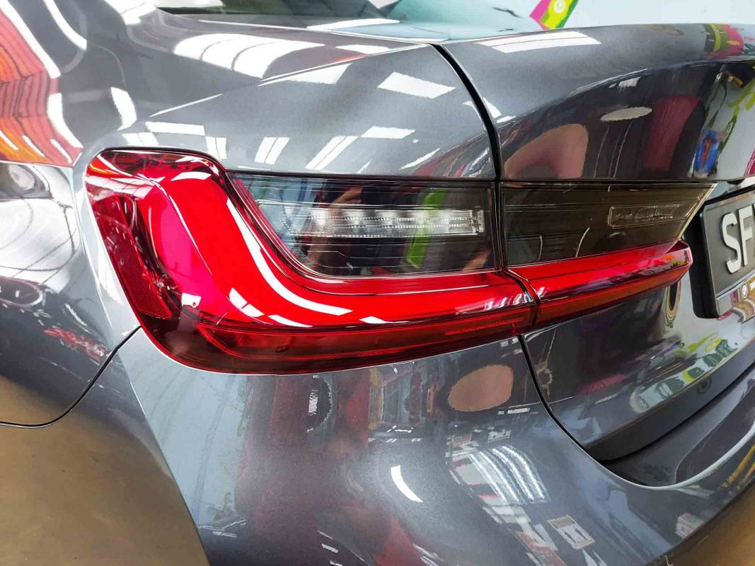 The coated bonnet of the BMW 318i under workshop lighting.