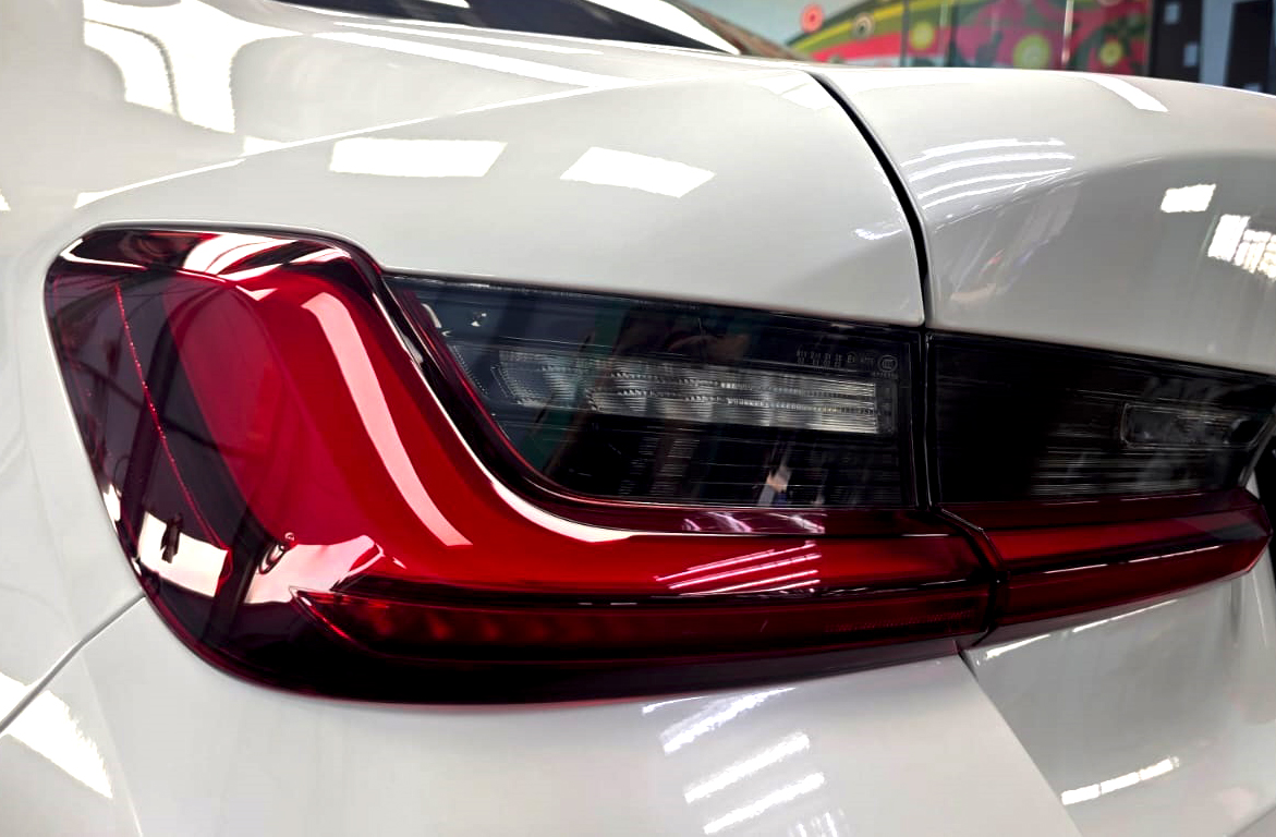 The coated bonnet of the BMW 318i under workshop lighting.