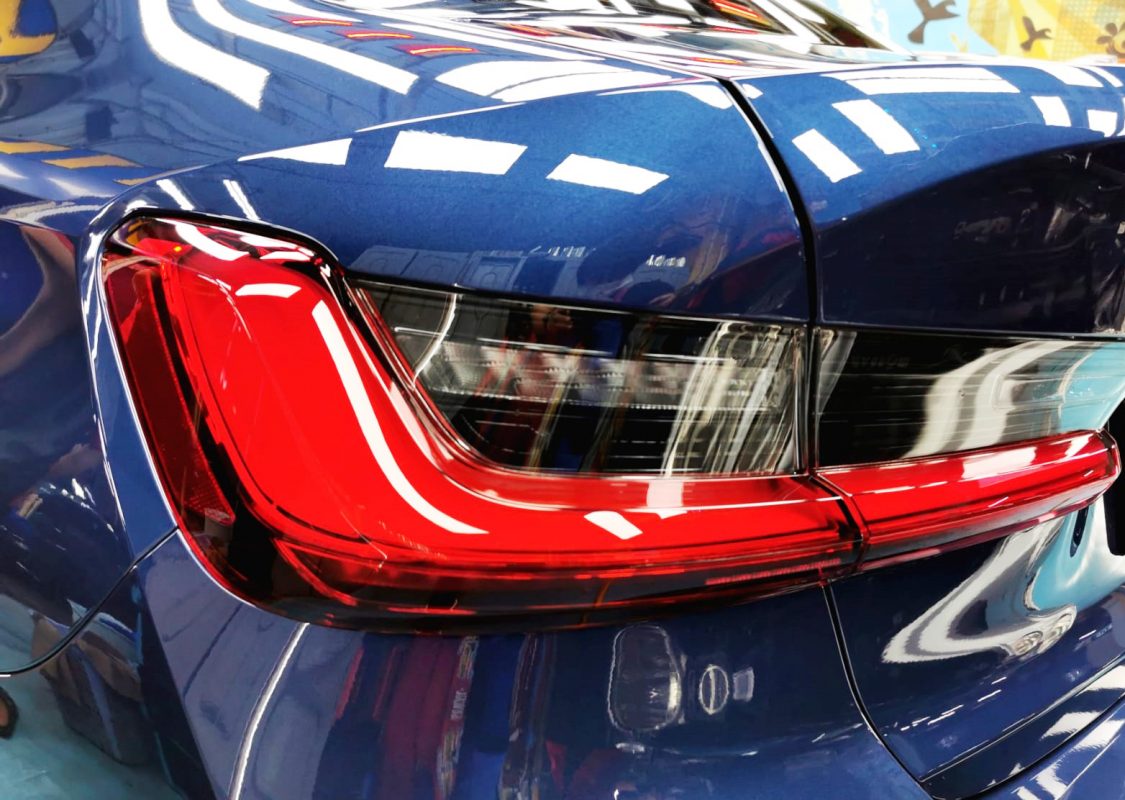 The coated bonnet of the BMW 318i under workshop lighting.