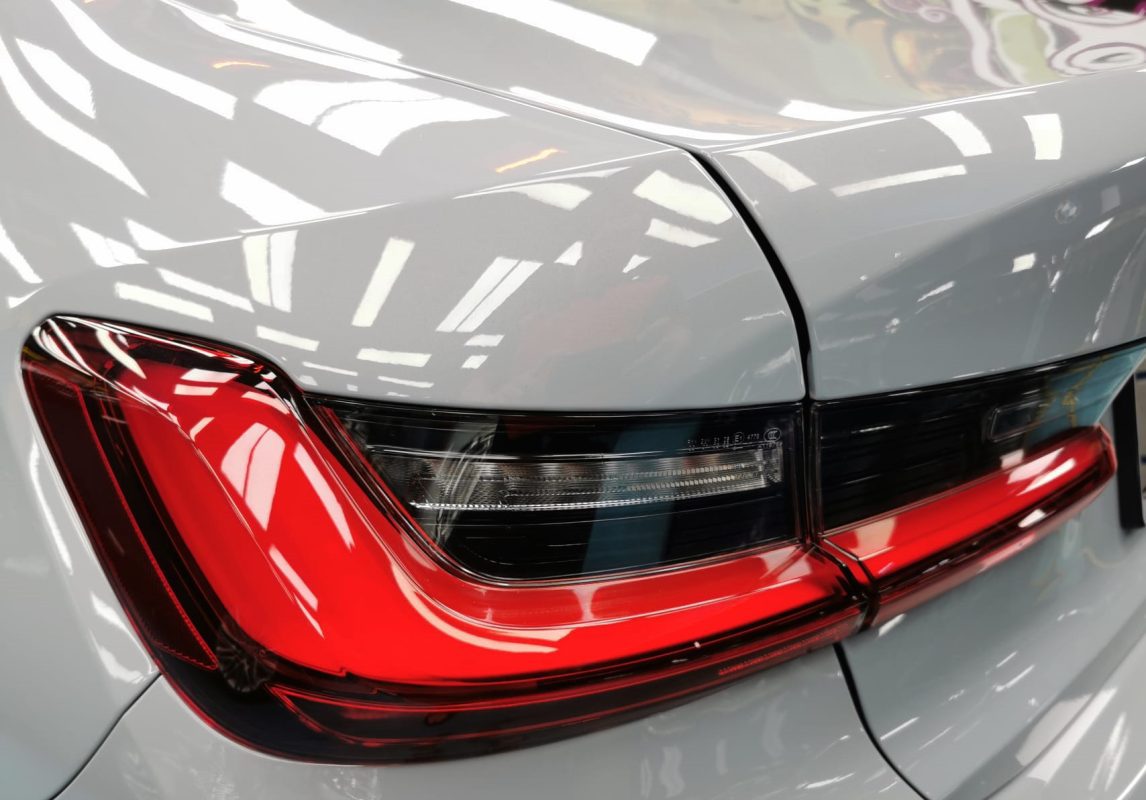 The coated bonnet of the BMW 318i under workshop lighting.
