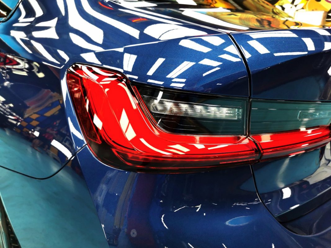 The coated bonnet of the BMW 318i under workshop lighting.