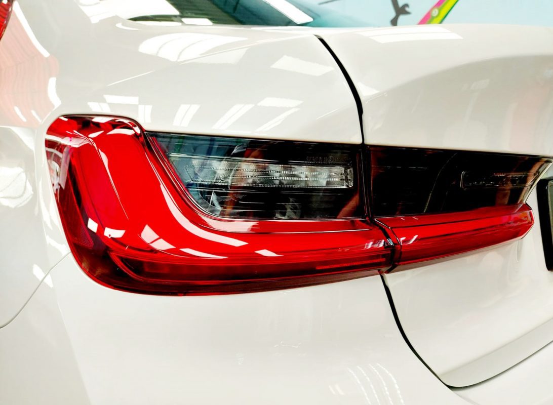 The coated bonnet of the BMW 318i under workshop lighting.