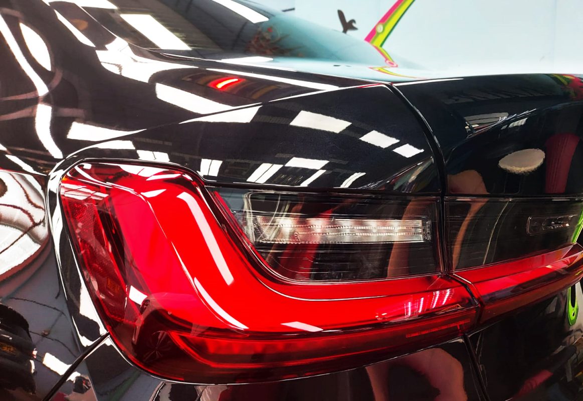 The coated bonnet of the BMW 318i under workshop lighting.