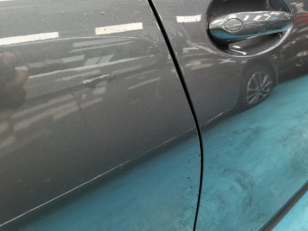 Side profile of the BMW 320i on arrival, stone chips and dull paint visible.