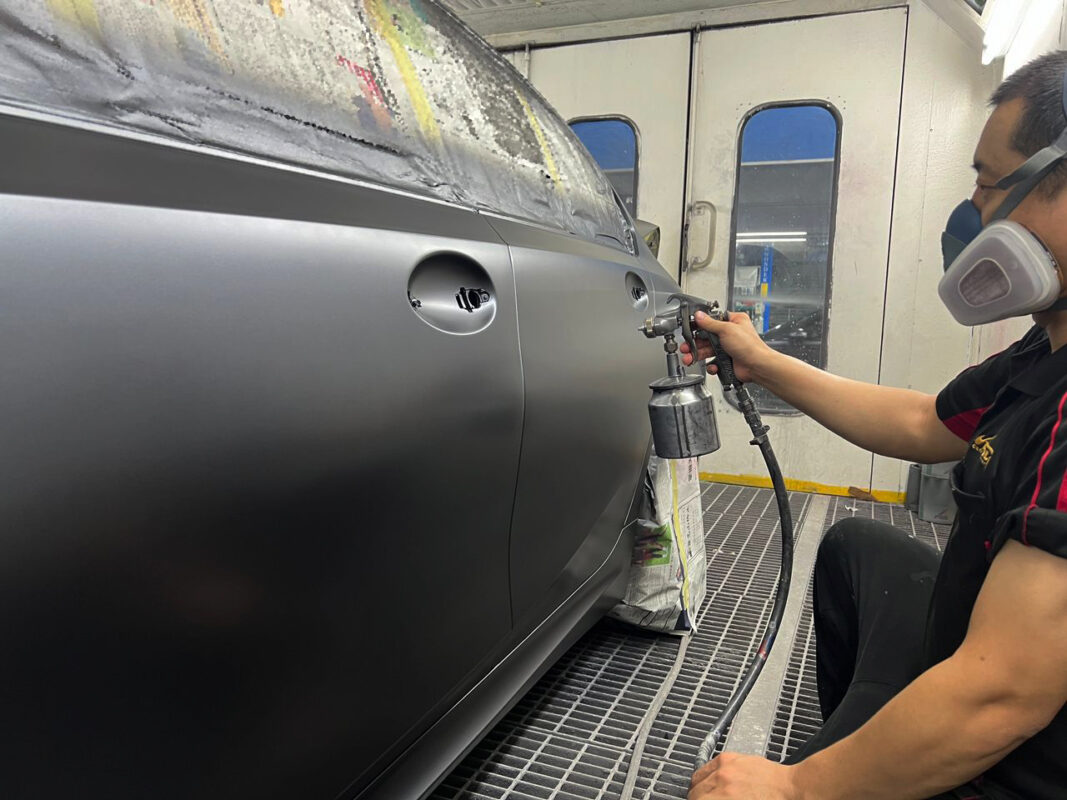 A Revol Carz painter spraying the fresh coat onto the BMW 320i in the spray booth.