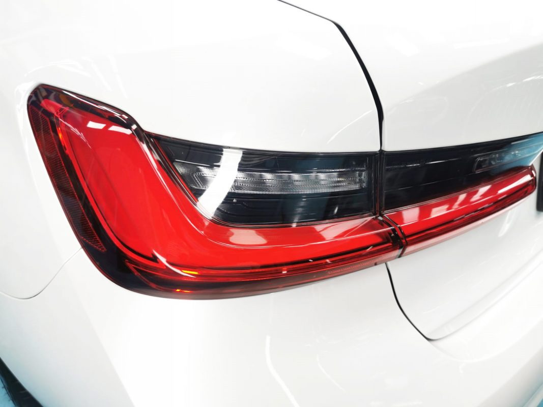 The coated bonnet of the BMW 320i under workshop lighting.