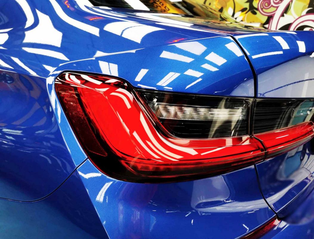 The coated bonnet of the 320i under workshop lighting.