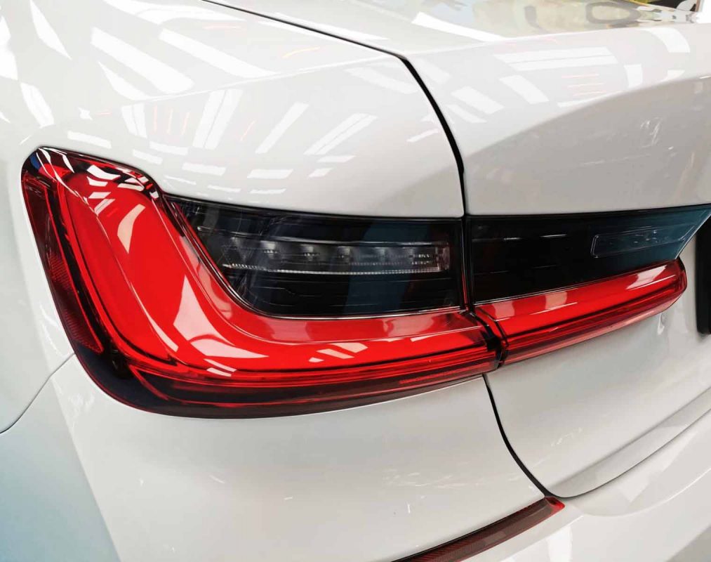 The coated bonnet of the BMW 330i under workshop lighting.