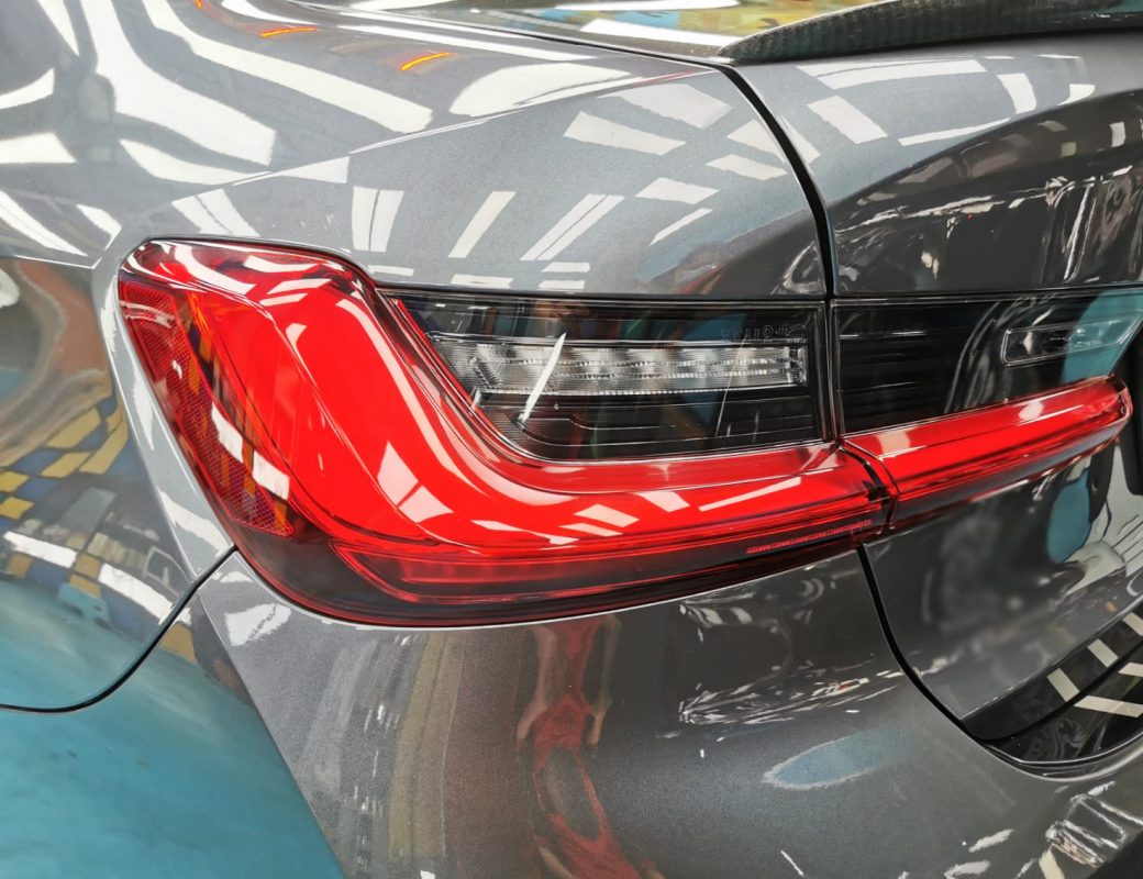 The coated bonnet of the BMW 330i under workshop lighting.