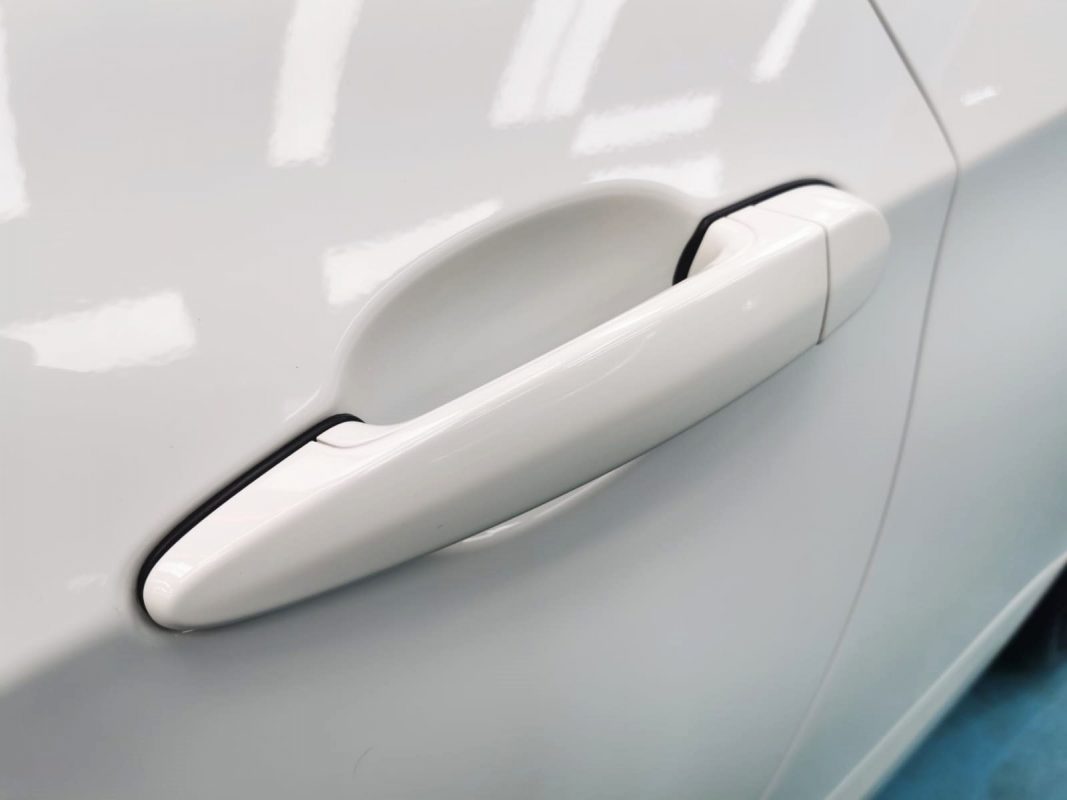 The coated bonnet of the BMW 335i under workshop lighting.