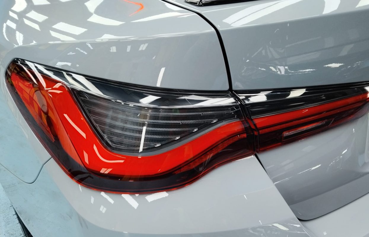 The coated bonnet of the BMW 4 Series under workshop lighting.