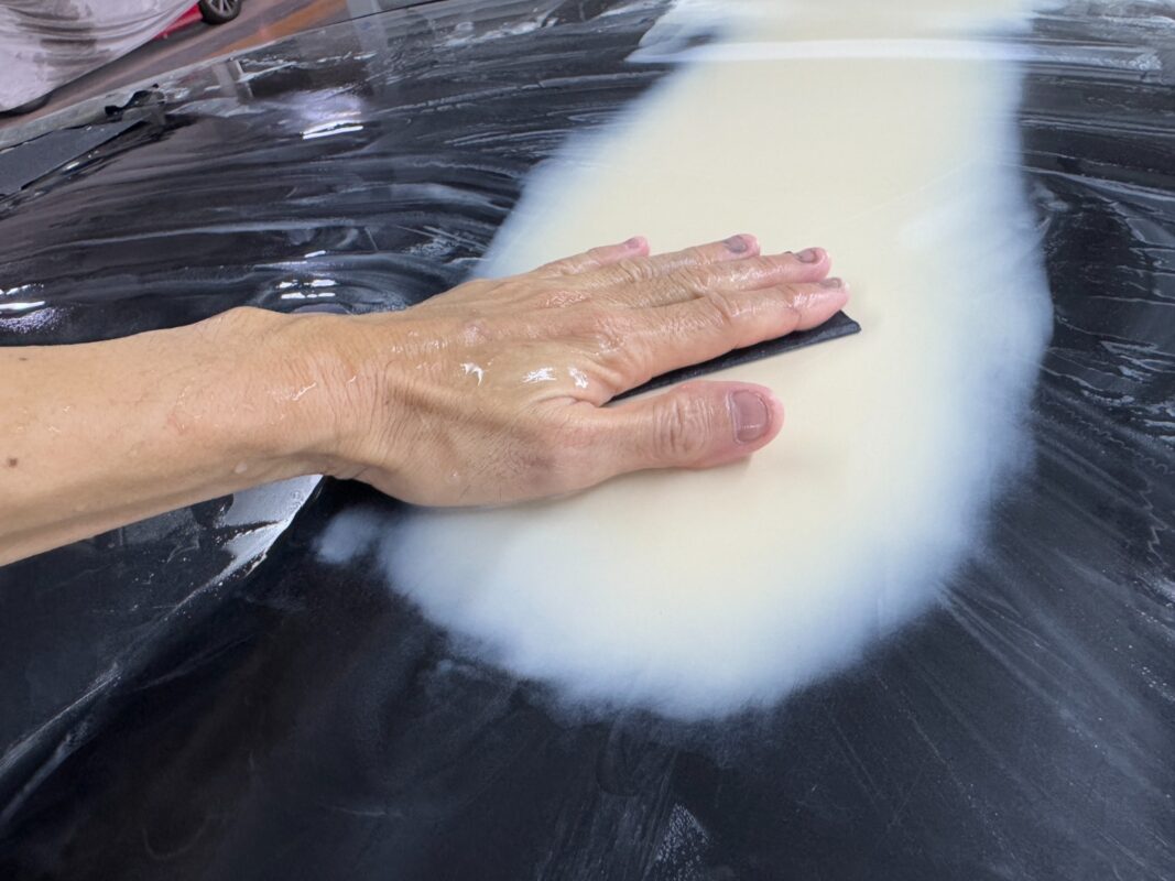 Wet-sanding the body of the BMW 4 Series to smooth the surface.