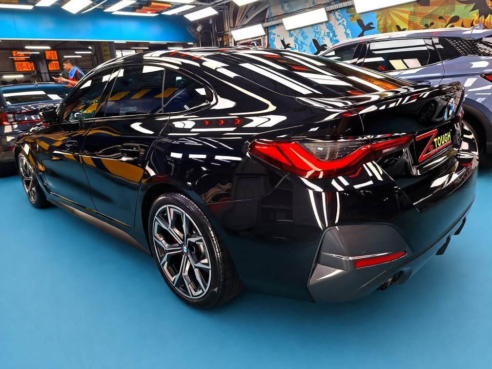 Rear three-quarter view of the black BMW 4 Series Gran Coupe showing the tail lights and rear diffuser.