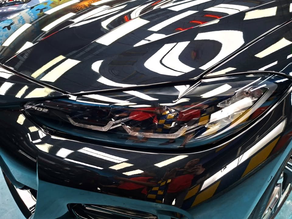 Close-up of the BMW 4 Series headlight with sharp light reflections in the black bonnet.
