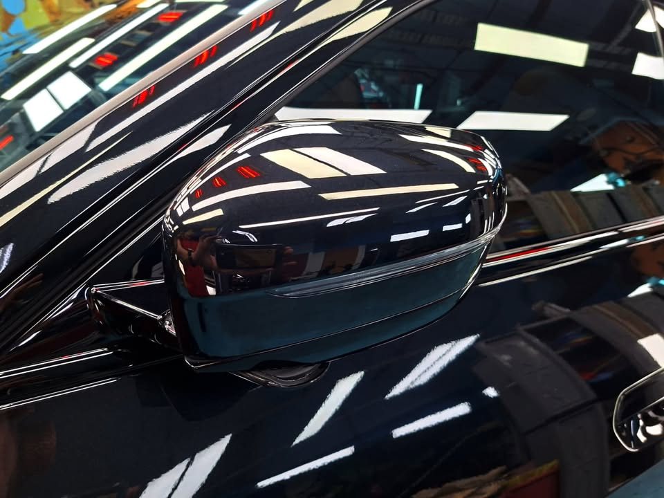 Close-up of the black door mirror on the BMW 4 Series reflecting the workshop lights.
