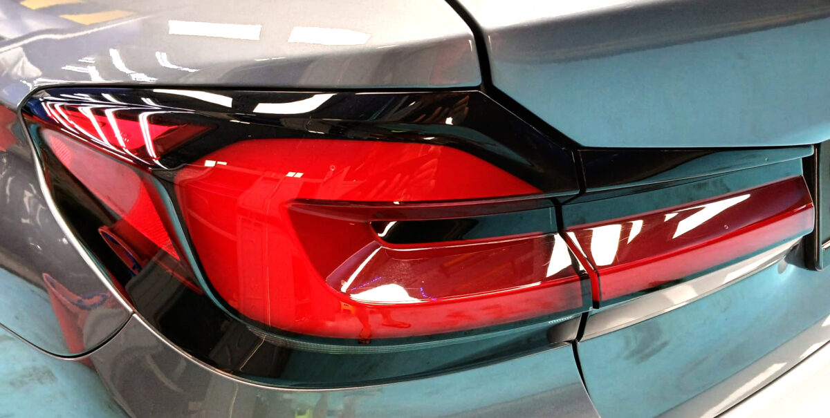 The coated bonnet of the BMW 5 Series under workshop lighting.