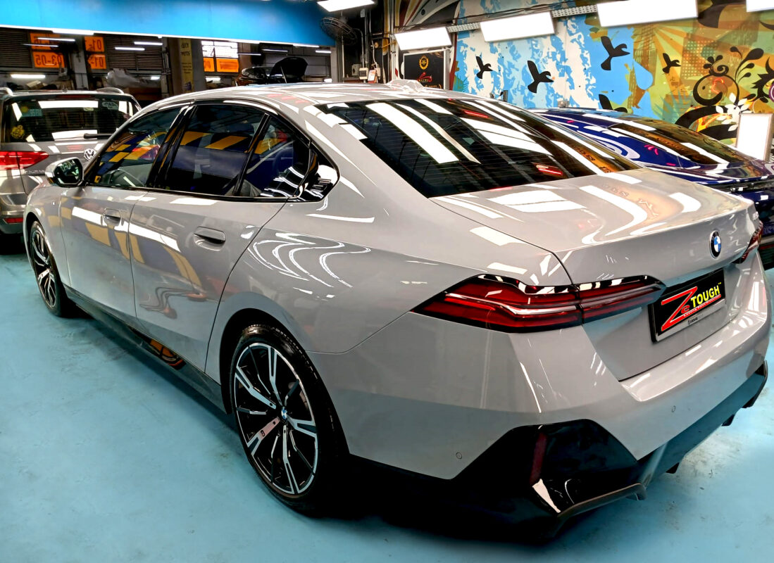 The coated bonnet of the BMW 5 Series under workshop lighting.