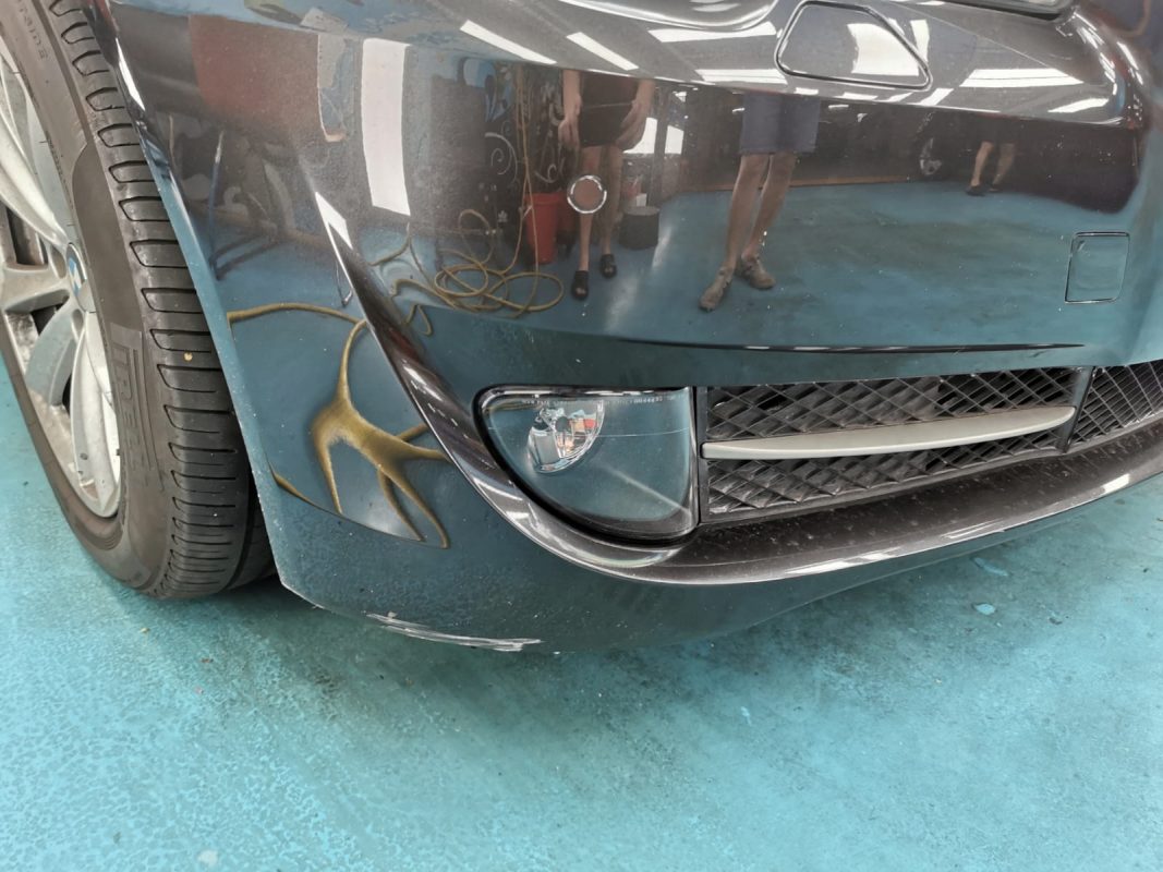 The BMW 5 Series at intake, showing a dent and scratches on the body.